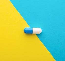 Biało-niebieska kapsułka loperamidu na żółto-niebieskim tle.