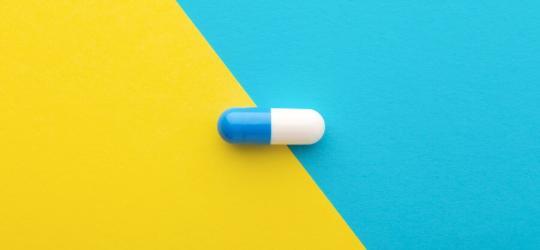 Biało-niebieska kapsułka loperamidu na żółto-niebieskim tle.