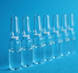 Szklane ampułki ustawione w szeregu na niebieskim tle.