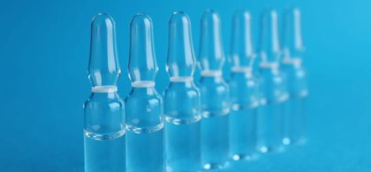 Szklane ampułki ustawione w szeregu na niebieskim tle.