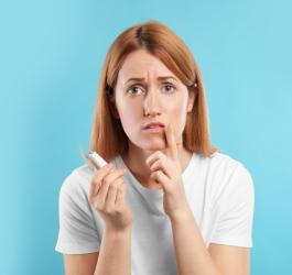 Kobieta nakłada maść na opryszczkę na ustach.