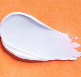 Maść z witaminą A rozsmarowana na pomarańczowym tle.