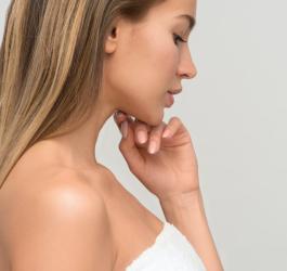 Kobieta po kąpieli owinięta białym ręcznikiem.