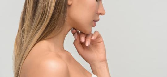 Kobieta po kąpieli owinięta białym ręcznikiem.