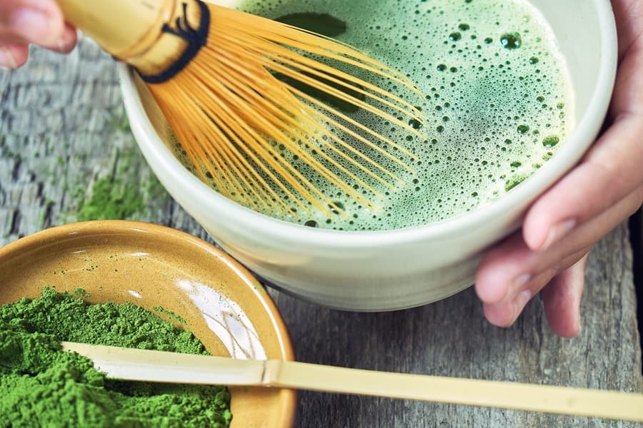Osoba przygotowuję herbatę matcha tradycyjnym sposobem.