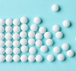 Białe tabletki ułożone na błękitnym tle.