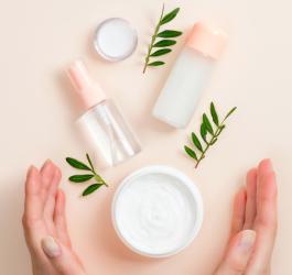 Kobiece dłonie obejmują opakowania z kosmetykami naturalnymi.