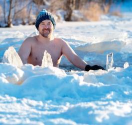 Mężczyzna w czapce i rękawiczkach. Morsuje w jeziorze zimą.
