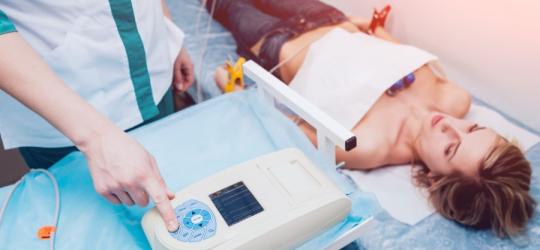Kobieta leży na leżance z podpiętą aparaturą do badania EKG.
