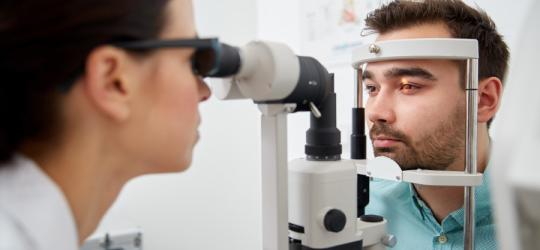 Mężczyzna bada się u okulisty w kierunku diagnostyki nadciśnienia w oku.