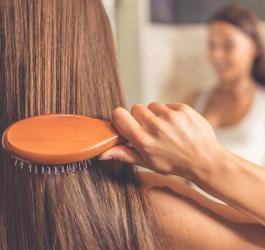 Kobieta rozczesuje włosy po wcześniejszym zabiegu z naftą kosmetyczną.