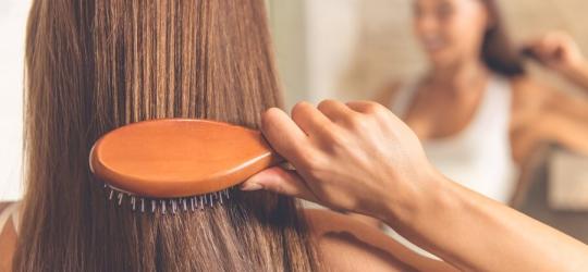 Kobieta rozczesuje włosy po wcześniejszym zabiegu z naftą kosmetyczną.