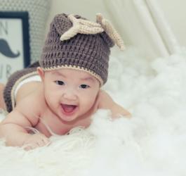 Uśmiechnięte niemowlę w szydełkowej czapeczce.