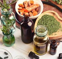 Świeże i suszone zioła oraz pipeta i butelki na drewnianym blacie.