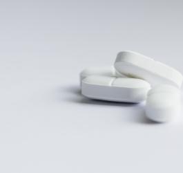 Białe tabletki na szarym tle.