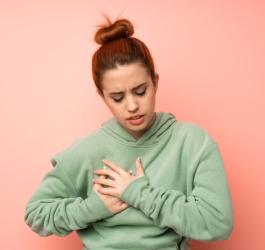 Kobieta trzyma się za klatkę piersiową, zmaga się z nerwicą serca.