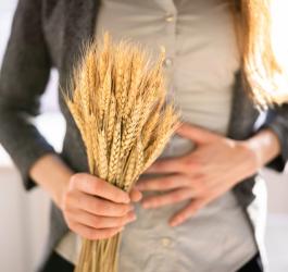 Kobieta trzyma w ręce kłosy pszenicy, cierpi na nietolerancję glutenu.