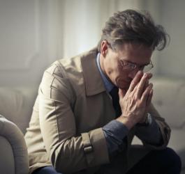 Zmartwiony mężczyzna siedzi na kanapie.