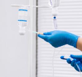 Pielęgniarka poprawia kroplówkę na stojaku.