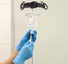 Pielęgniarka podłącza kroplówkę i zawiesza ją na stojaku.