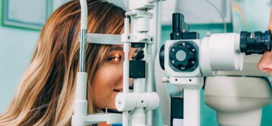 Kobieta ma wykonywane badanie dna oka w gabinecie okulistycznym.