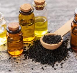 Olej z czarnuszki w buteleczkach oraz nasiona czarnuszki.