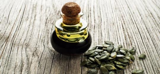 Butelka oleju z pestek dyni i pestki dyni na drewnianym blacie.