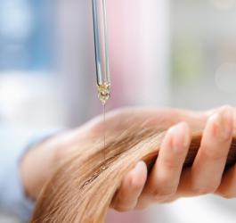 Kosmetyczka wykonuje u klientki olejowanie włosów.