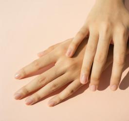 Zadbane, kobiece dłonie na różowym tle.