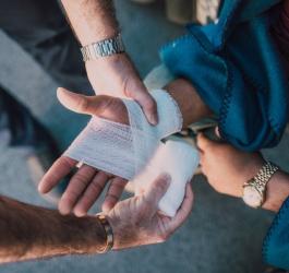 Mężczyzna opatruje dłoń kobiety, która uległa wypadkowi.