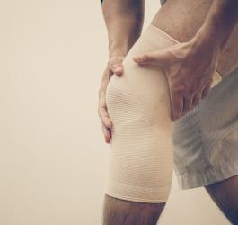 Mężczyzna zakłada opaskę na kolano.