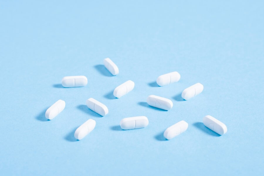 Białe tabletki na błękitnym tle.