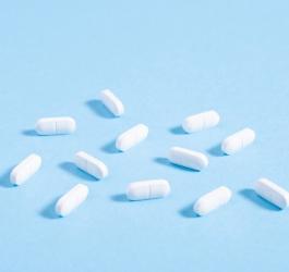 Białe tabletki na błękitnym tle.