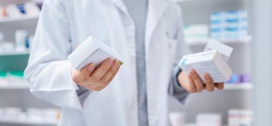 Farmaceuta trzyma w rękach pudełka leków.