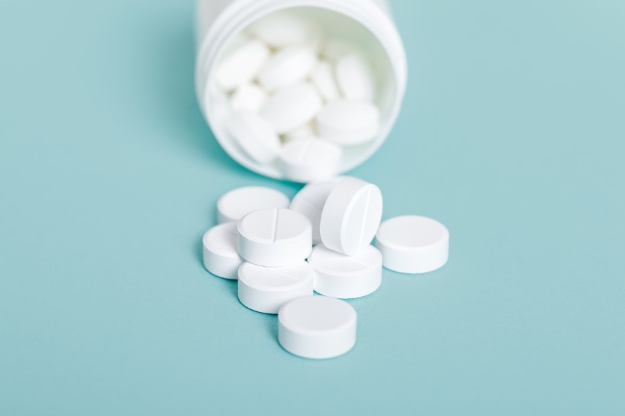 Białe tabletki wysypują się z buteleczki.