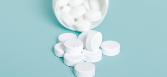 Białe tabletki wysypują się z buteleczki.