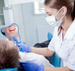 Pacjent u stomatologa, po piaskowaniu zębów ogląda efekty czyszczenia w lusterku.