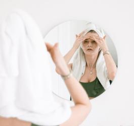 Kobieta po kąpieli nakłada na twarz kosmetyki pielęgnacyjne.