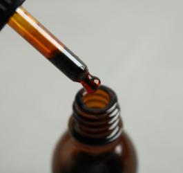 Buteleczka z ciemnego szkła wraz z pipetą. W środku płyn Lugola.