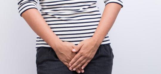 Kobieta trzyma dłonie na wysokości narządów rodnych. Może cierpieć na pochwicę.