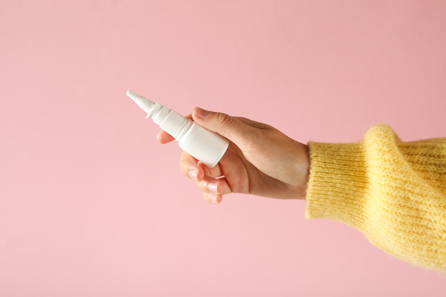 Osoba w żółtym swetrze trzyma w dłoni lek na zapalenie zatok.