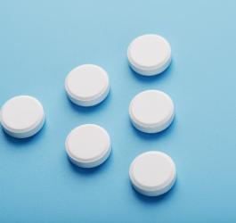 Białe tabletki ułożone w kształt trójkąta na błękitnym tle.