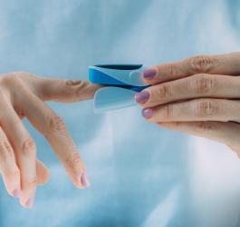 Kobieta zakłada pulsoksymetr na palec wskazujący.