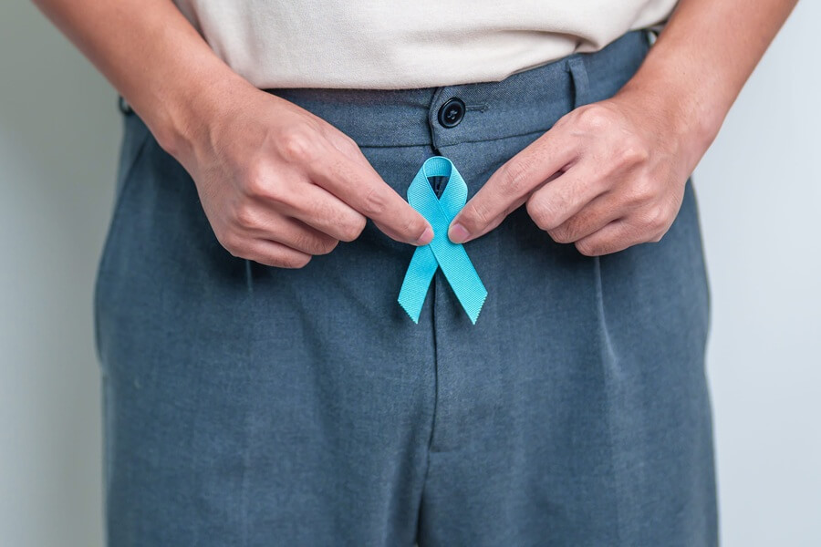 Mężczyzna trzyma niebieską wstążkę – symbol walki z rakiem prostaty