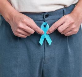 Mężczyzna trzyma niebieską wstążkę – symbol walki z rakiem prostaty