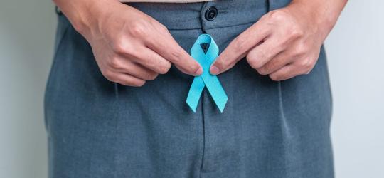 Mężczyzna trzyma niebieską wstążkę – symbol walki z rakiem prostaty