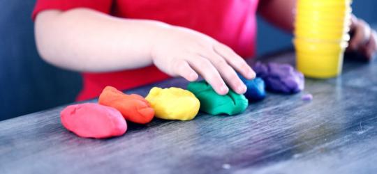 Dziecko bawiące się kolorową masą plastyczną.