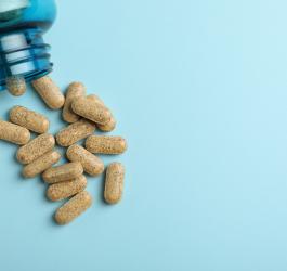 Tabletki z ashwagandhą wysypujące się z niebieskiej buteleczki.