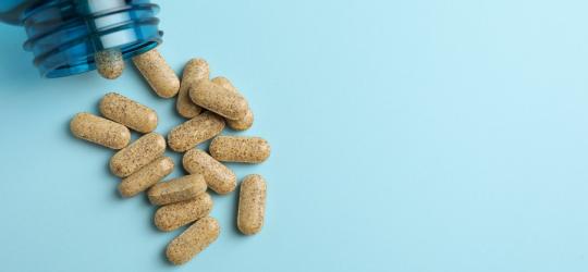 Tabletki z ashwagandhą wysypujące się z niebieskiej buteleczki.