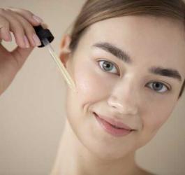 Kobieta nakłada na skórę płynne serum za pomocą pipety.